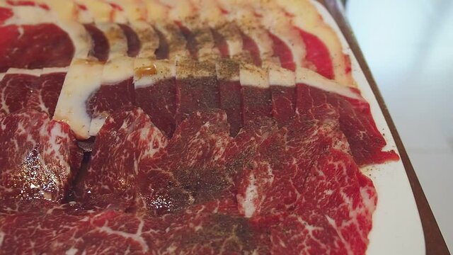 Raw Wagyu A5 beef sliced with marbled texture served for Sukiyaki and Shabu or Yakiniku. Japanese food. Panning left.