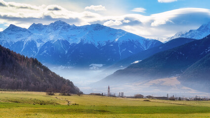 View to Burgusio-Burgeis in the Vinschgau Valley with morning mist in wintertime