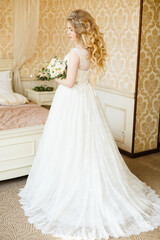 Fototapeta na wymiar Pretty young Bride. Blonde woman with luxurious long curly hair. Boudoir morning of the bride. 