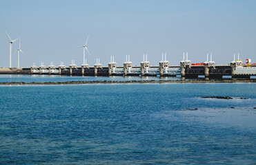 Netherlands, August 2019. In Zeeland, wind farms are the setting for the immense dam that governs the flow of sea waters, securing the territory.