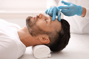 Obraz na płótnie Canvas Plastic surgeon injecting hyaluronic acid in man forehead