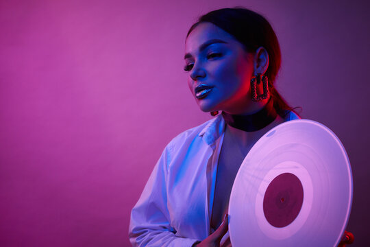 Disco Woman Portrait Holding A Retro Vinyl With 80s Music On Neon Light Background.