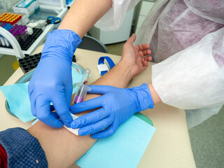 A Nurse In The Clinic Inserts A Catheter Into A Vein For Blood Testing For A man. blue medical gloves. close up.