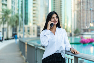 Fototapeta premium Successful businesswoman talking on cellphone while walking outdoor.