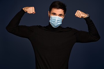 Strong man in sterile face mask posing isolated on Pacific Blue background studio portrait....
