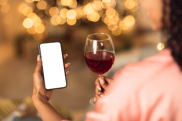 Black woman holding phone with empty mockup screen, drinking wine