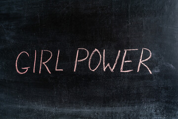 The phrase "Girl power" on a black chalk board.