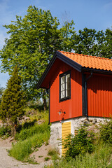 Fototapeta na wymiar Red summer garden cottage in Sweeden. Traditional Sweden wooden old house. Life on the one of Sweeden islands