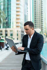 Fototapeta premium Handsome young man working on laptop outdoors. Concept of work life balance.