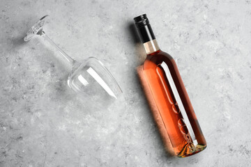 Rose wine in bottle and wine glass on gray concrete grunge background flat lay. Concept wine degustation. View from above
