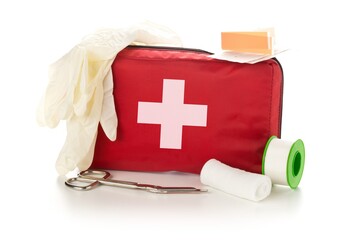 Red first aid medical kit bag with scissors, tape and gloves standing over white