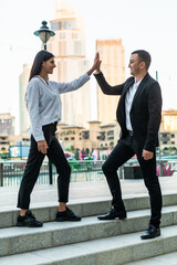 Businessman and business woman doing high five outdoors. Business concept. Successful concept....
