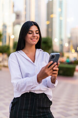 Fototapeta premium Business woman uses smartphone outdoors in big city with skyscrapers in the background.