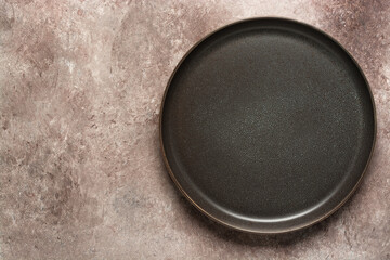 Empty craft plate in gray-brown on beige grunge background. Top view, flat lay.