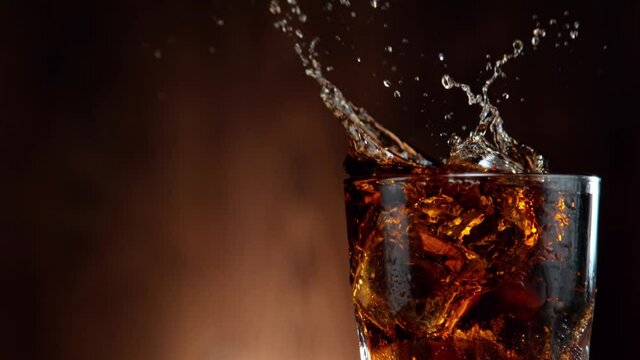 Super slow motion of falling ice cube into cola drink, camera movement. Filmed on high speed cinema camera, 1000 fps