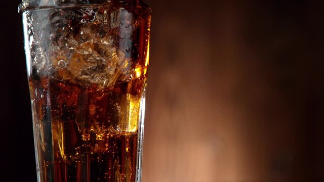 Super slow motion of falling ice cube into cola drink, camera movement. Filmed on high speed cinema camera, 1000 fps