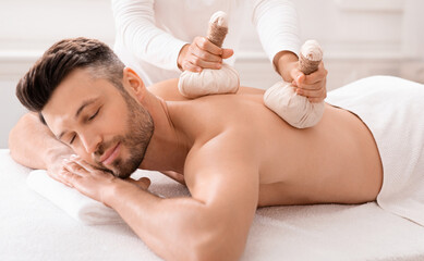 Obraz na płótnie Canvas Spa therapist making body massage with herbal compress balls