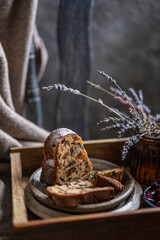 A piece of a sponge or bundt cake with dried fruits on a wooden tray with lavender flowers on a rustic chair. Beautiful desert or breakfast, copy space. Homemade freshly baked pie.
