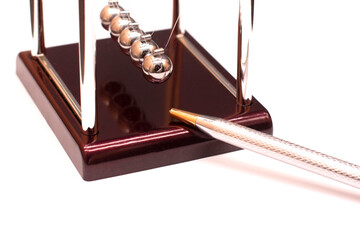 Newton's cradle and silver pen on the desktop in the office
