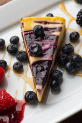 Cheesecake. Traditional Classic New York Style cheesecake dessert topped with fresh starwberry and a a strawberry sauce. A bakery or pastry shop favorite. 