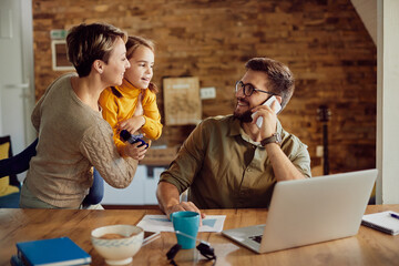 Happy father talking to his family while working at home.