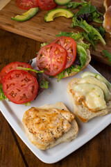 Chicken tender sandwich. Traditional classic american restaurant favorite menu item. Crispy chicken tenders served with bacon lettuce tomato onion and guacamole on a toasted bun.