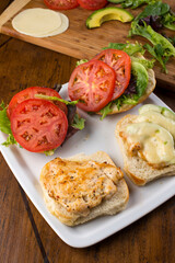 Chicken tender sandwich. Traditional classic american restaurant favorite menu item. Crispy chicken tenders served with bacon lettuce tomato onion and guacamole on a toasted bun.