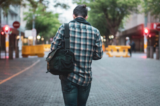 Young Man Walking in Urban City With Trees in the Background