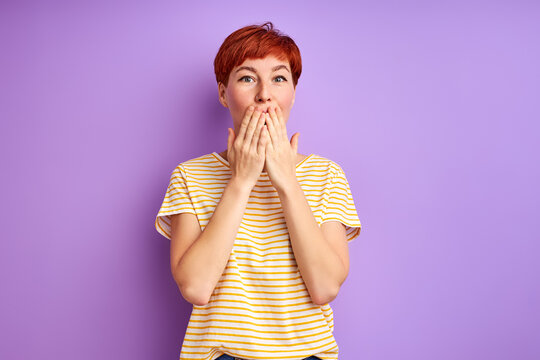 Redhead Woman Stand Closing Mouth, In Shock. Isolated Over Purple Background