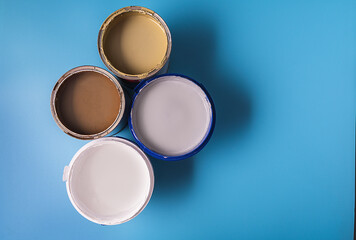 Cans with paint of different colors on blue background.