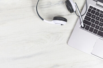 Laptop. keyboard and headphones on grey desk and plain wooden background banner. Helpdesk or call center headset. Distant learning or working from home, online courses or support center concept. - obrazy, fototapety, plakaty