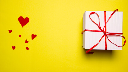Gift box on the yellow background. Red ribbon. Valentines Day gift. Copy space with place fot text.