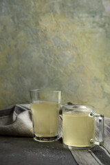 Homemade beef bone broth in a clear glass mug on a gray-yellow background. bone broth with collagen content, which provides the body with amino acids and protein