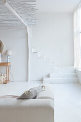 Cozy interior of a bright Balinese-style apartment with white walls, bamboo chair, big white sofa and decorations © 4595886