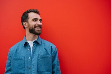 Young smiling man wearing stylish casual shirt isolated on red background. Copy space, advertising concept