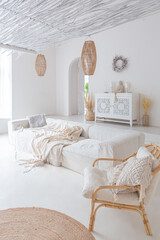 Cozy interior of a bright Balinese-style apartment with white walls, bamboo chair, big white sofa and decorations © 4595886