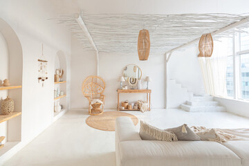 Cozy interior of a bright Balinese-style apartment with white walls, bamboo chair, big white sofa and decorations © 4595886