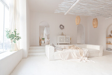 Cozy interior of a bright Balinese-style apartment with white walls, bamboo chair, big white sofa...