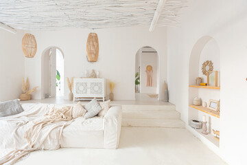 Cozy interior of a bright Balinese-style apartment with white walls, bamboo chair, big white sofa...