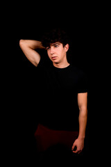 Fototapeta na wymiar Attractive young man with curly hair posing on black studio background