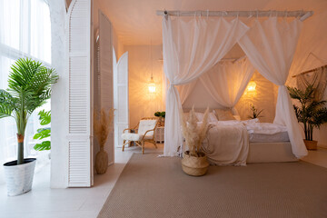 Cozy interior of a bright Balinese-style apartment with white walls, bamboo furniture. bed room with night lights, bed with balanchin and large windows © 4595886