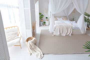 Cozy interior of a bright Balinese-style apartment with white walls, bamboo furniture. bed room with night lights, bed with balanchin and large windows © 4595886