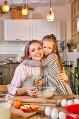 daughter hugging mother while cooking, caucasian family preparing dough, bake cookies, look at camera smiling