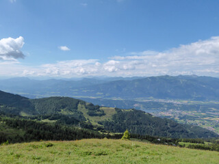 The panoramic view on the vast valley with a few cities seen from a lush green pasture in Austrian...