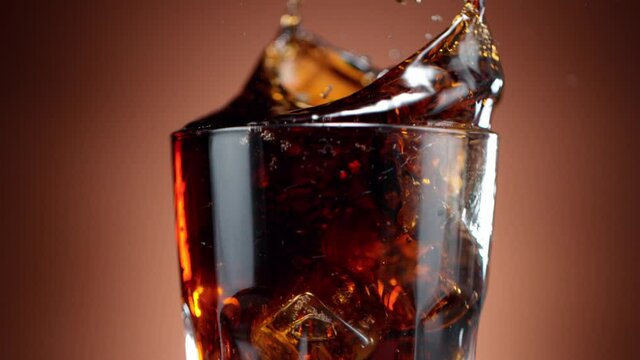 Super slow motion of falling ice cube into cola drink, camera movement. Filmed on high speed cinema camera, 1000 fps