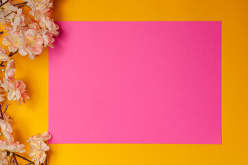 bouquet of pink flowers on the left side on a yellow background and a pink leaf