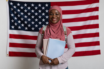 Smiling black woman in hijab standing over american flag