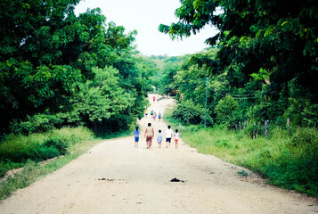 people walking on a dirt path in a rural area 