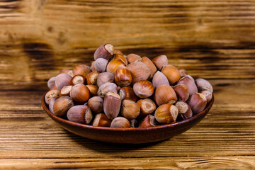 Plate with pile of hazelnuts on a wooden table