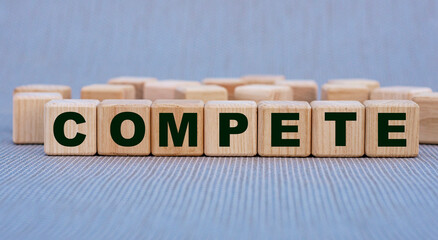 COMPETE - word on wooden cubes on a beautiful gray background